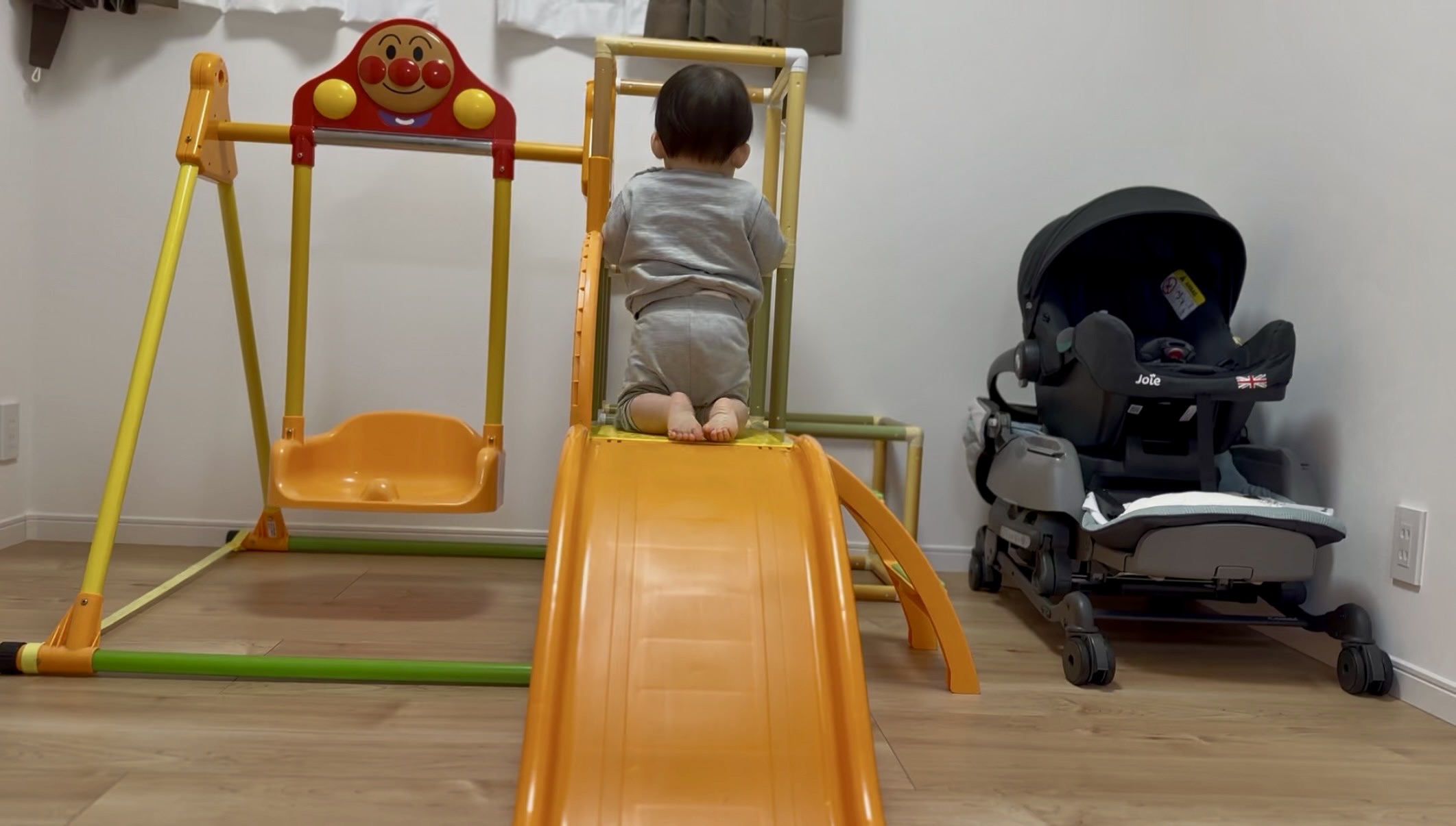 ジャングルジムのすべり台上に座る1歳の息子の後ろ姿