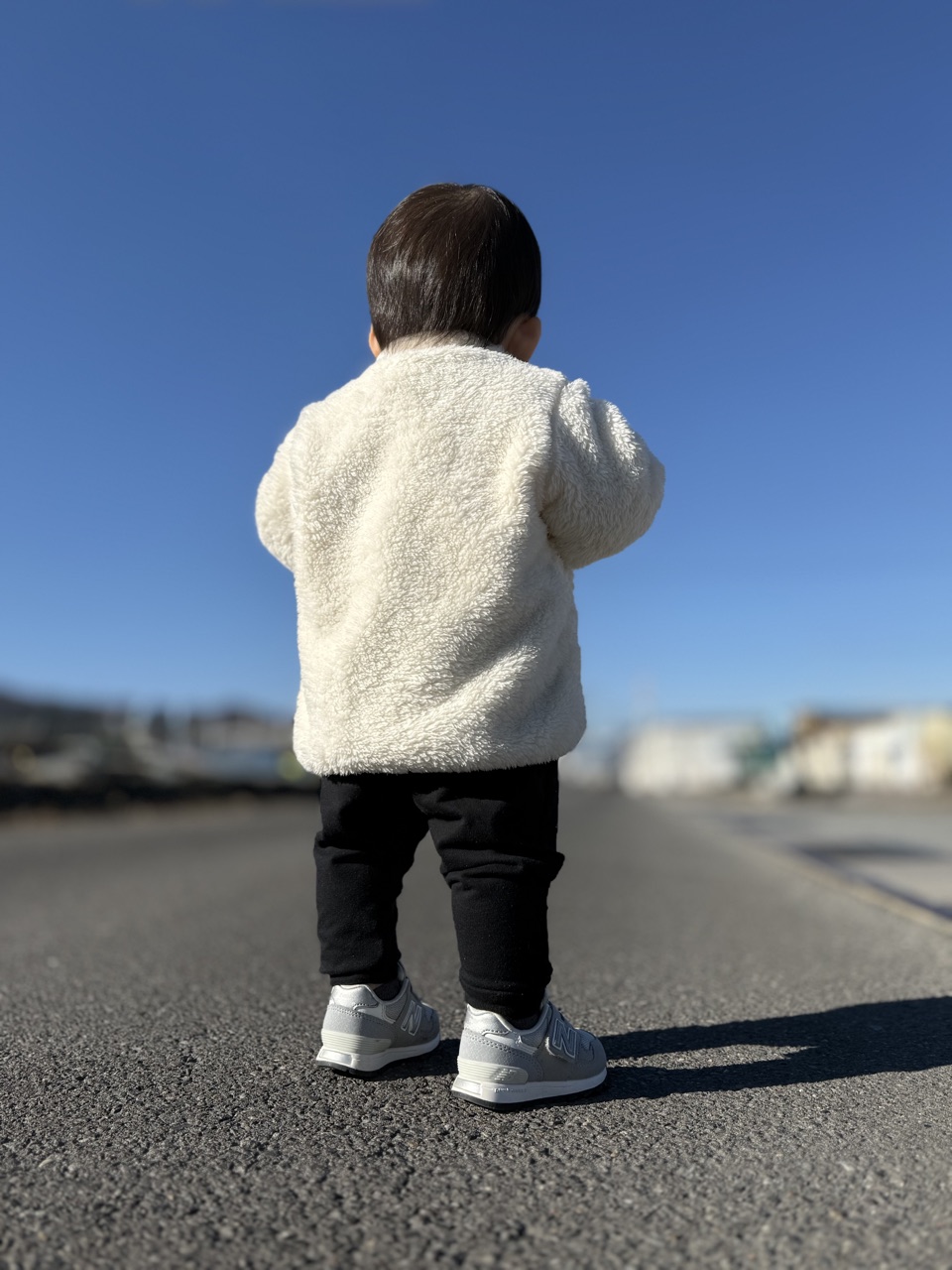 ニューバランスIO313(白)を履いて青空の下を歩く子どもの後ろ姿