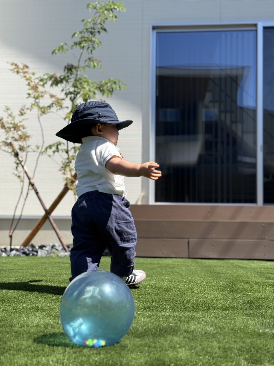 サンシールドハットをかぶって庭でボール遊びをする子ども