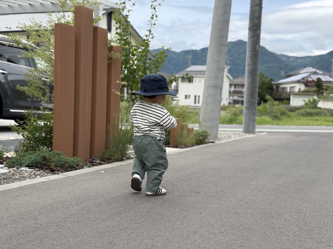 サンシールドハットをかぶって屋外を歩く子どもの後ろ姿