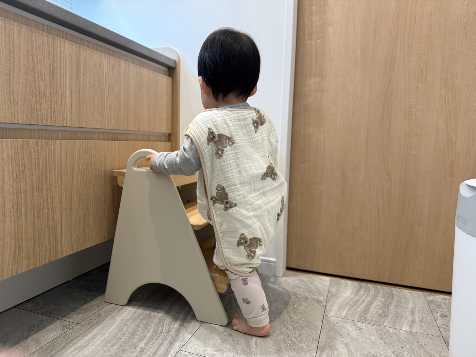 踏み台のハンドルをつかんで登ろうとする1歳の子ども