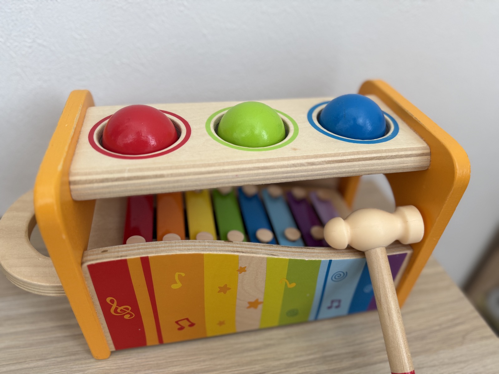 Hape パウンドアンドタップベンチの全体。木製の台に赤・緑・青の3つのボールが並び、下段に虹色の鉄琴が見える