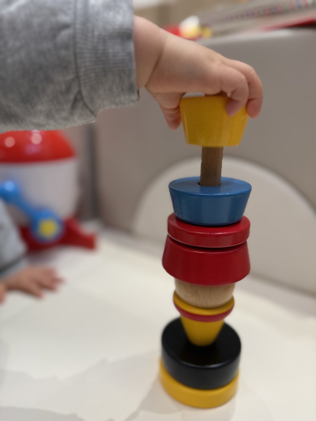BRIOクラウンのパーツを棒に通そうとしている1歳半の手