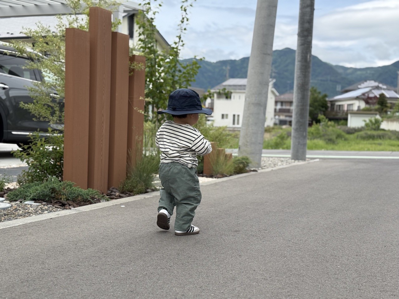 サンシールドハットをかぶって屋外を歩く子どもの後ろ姿