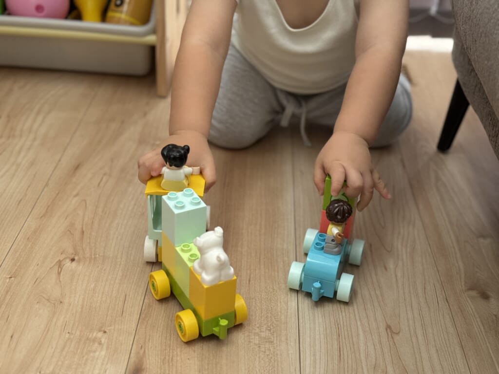 1歳の子どもがかずあそびトレインを床で走らせているところ