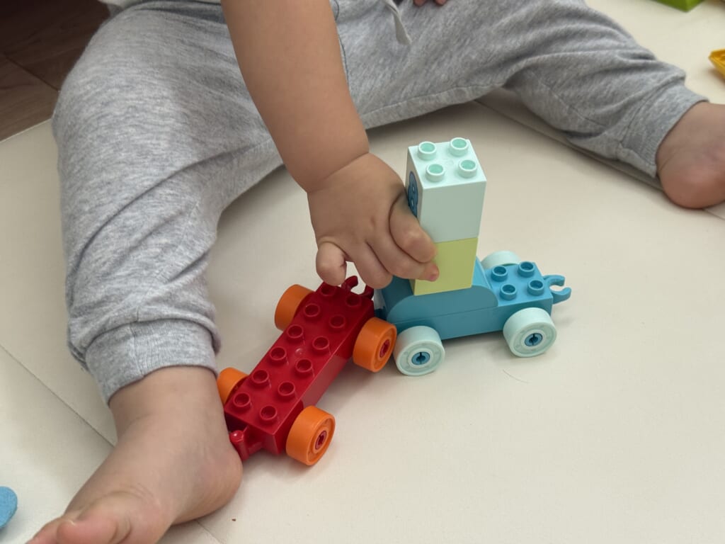 1歳の子どもがデュプロのブロックを組もうとしているところ