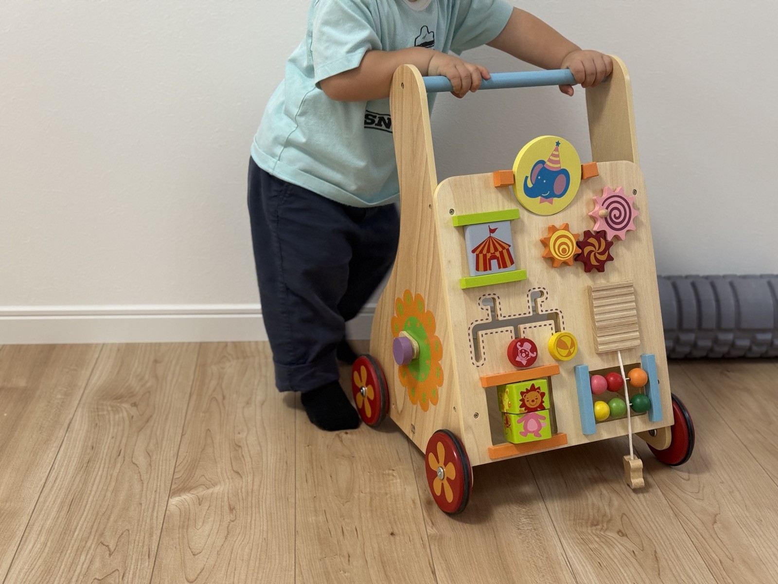ハンドルを両手で持って手押し車を押して歩く子ども